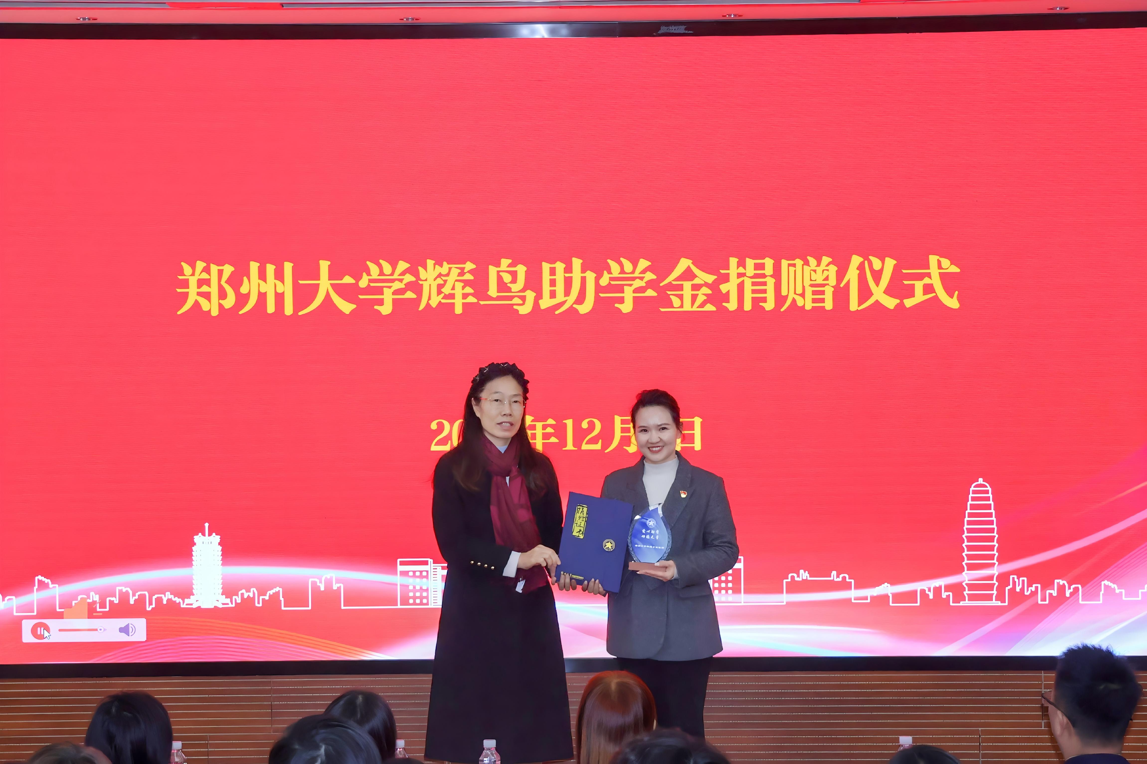 郑州大学物理学院副院长王杰芳向捐赠方辉鸟集团公司代表刘洁颁发捐赠证书及纪念杯.jpg 郑州大学物理学院副院长王杰芳向捐赠方辉鸟集团公司代表刘洁颁发捐赠证书及纪念杯.jpg